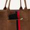 A closeup of The Classic Tote in ReVelvet Cinnamon Stripe, focusing on the exterior zip pocket. 